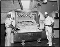 Two men posing next to a Ry-Krisp batter-mixing machine.