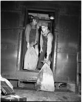 Railway Mail Service clerks load mail bags onto a Great Northern Railway Post Office car at the St. Paul Union Depot.