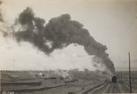 An Oliver Mining Company locomotive hauls ore away from an open pit near Hibbing, Minnesota, 1917. The young city is visible in the background.
