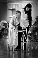 Therapist assists elderly stroke victim with a walker, Abbott-Northwestern Hospital, Sister Kenny Pavilion.