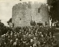 Black and white photograph of a reunion of First Minnesota Volunteer Infantry Regiment, posed in front of Round Tower, 1902.