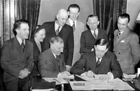 Black and white photograph of Governor Elmer Benson signing a barbers’ fair trade bill. Photograph by the St. Paul Daily News, 1937.