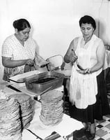 Black and white photograph of Mrs. Julio Lopez and Mrs. Francisco Rangle prepare food for an Mexican Independence celebration, Our Lady of Guadaloupe Church, September 15, 1958.