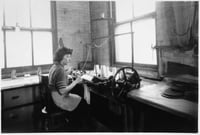 Black and white photograph of an employee knitting a sock to cover an amputated limb, Winkley Artificial Limb Company, Minneapolis, 1937.