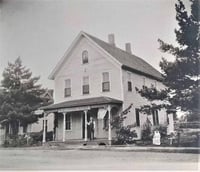 Three unidentified people in front of the Nerstrand Hotel with American flags on display, ca. 1890. Nerstrand city records, Nerstrand City Hall.