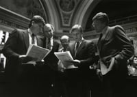Black and white photograph of Ron Dicklich, William Luther, Allan Spear, Roger Moe, and Duane Benson reading a bill on the floor of the Minnesota Senate, 1988.