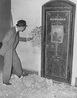 Black and white photograph of Richard Sackett examining the Minnesota Historical Society vault door in the second capitol building prior to its demolition, 1937.