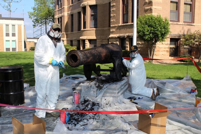 On site conservation of cannon by two workers 