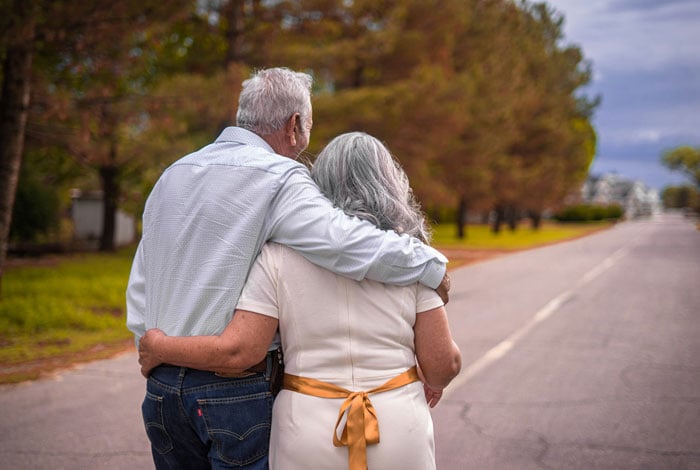 Couple hugging on the road during daytime.
