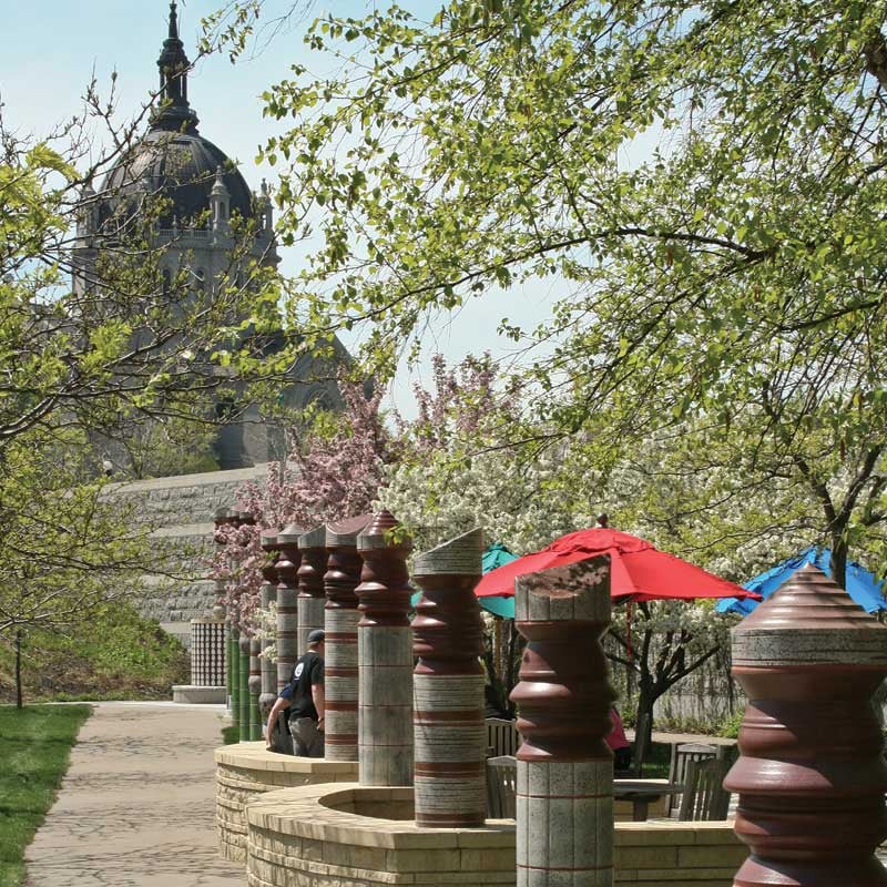 Rounded beams stand in a line with the St. Paul Cathedral in the background. Brooks Family Courtyard.