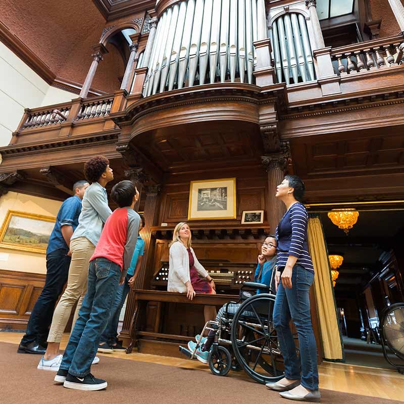 A group of people peering up at a large organ built inside the James J. Hill House.