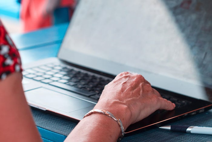 Senior woman hand typing on laptop.