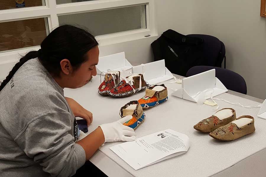 A man studies moccasins at a table.