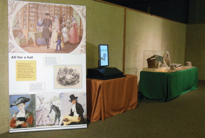 A large display panel stands next to a table with a screen.