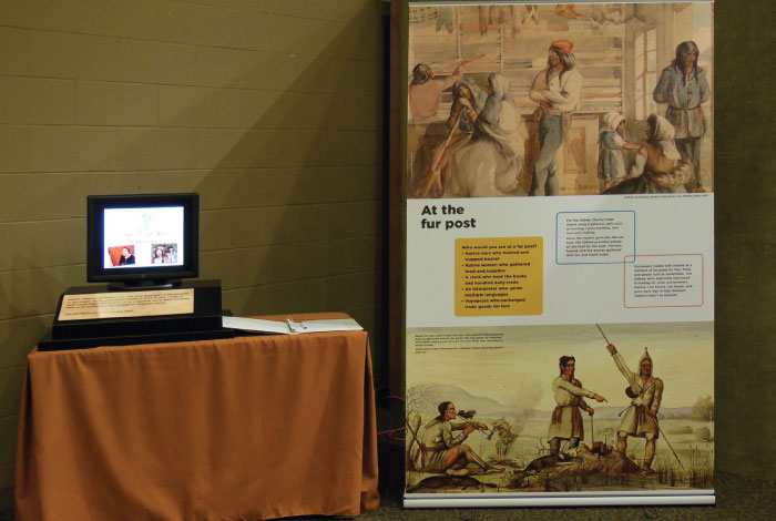 Floor-stand exhibit signage standing next to a table with smaller exhibit signage.