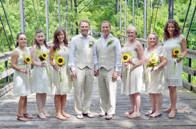 A wedding party poses together on a bridge.