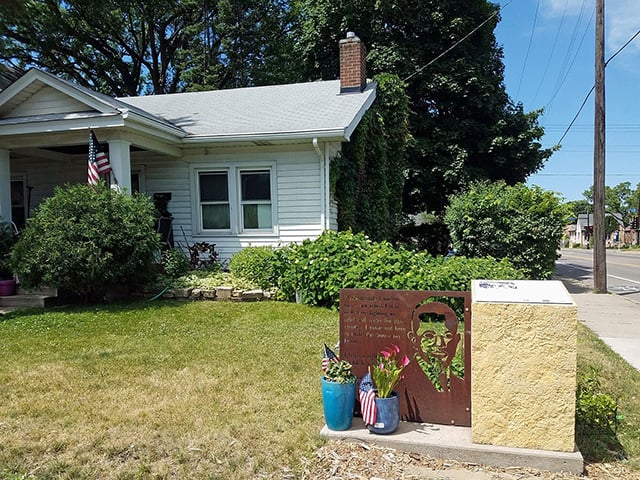 White bungalow and lawn with a historic marker at the bottom right.