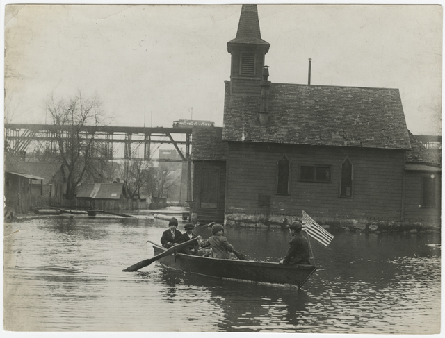Boys rowing a boat down a flooded street in Bohemian Flats