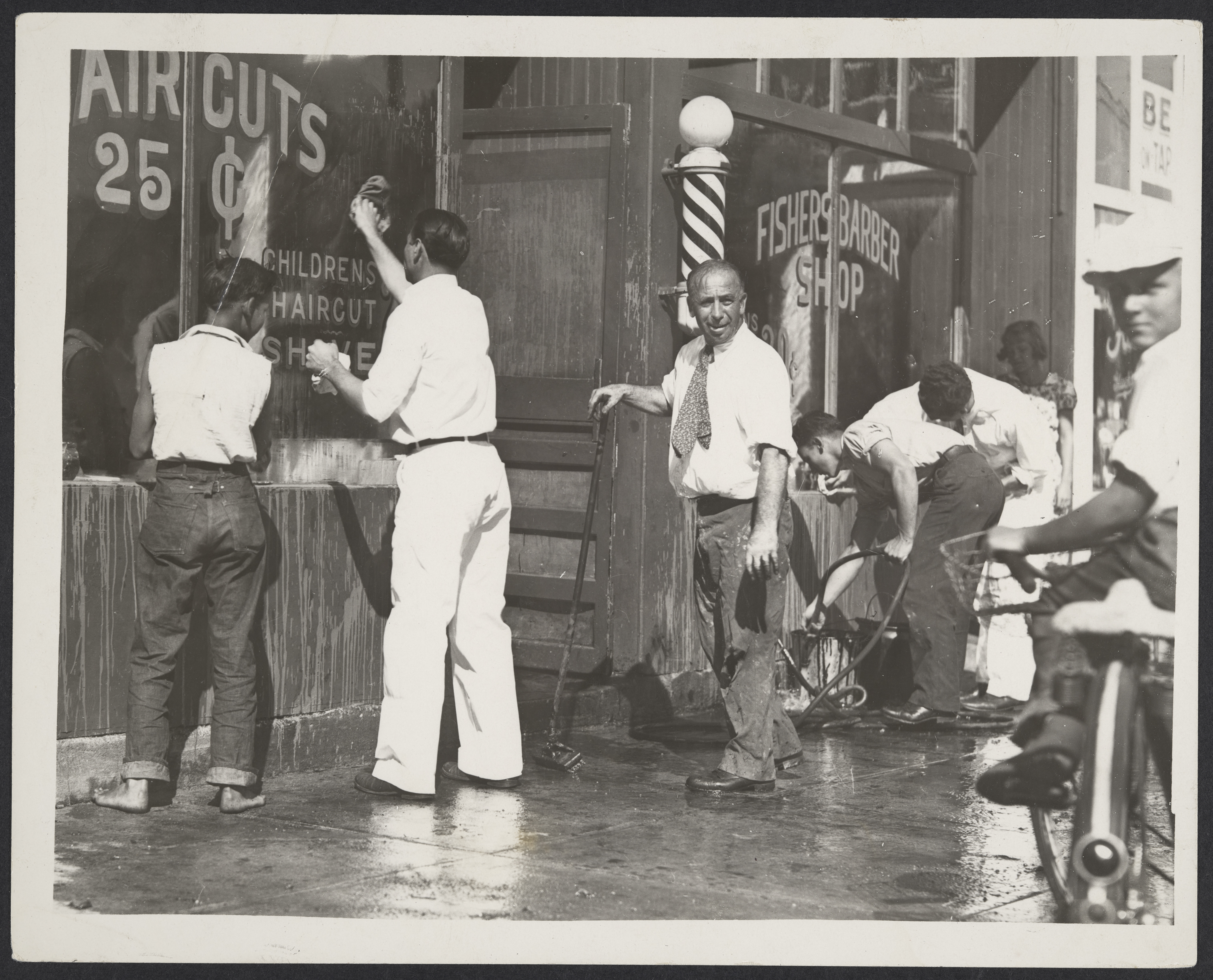 Black and white photograph of the exterior of Fisher’s Barber Shop splashed with red paint, c.1940s.