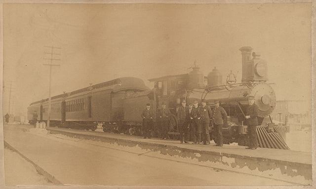 St. Paul and Duluth Railroad Company train and several railroad men, including John Wesley. Blair was an African American porter on the Eastern Minnesota train that rescued hundreds of people from the fire in Hinckley. He was honored as one of the heroes. He is second from the right in the photograph.