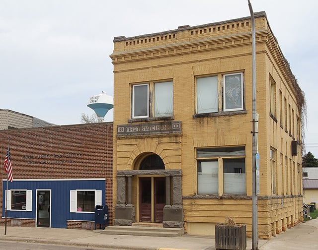 A brick one-story building with a blue facade on the lower story next to a two-story yellow-brick building.