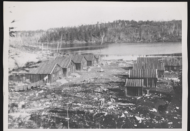 Log structures on a deforested piece of land next to a river.