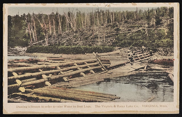 Wood logs and a fence-like structure laid over a stream as a makeshift dam.