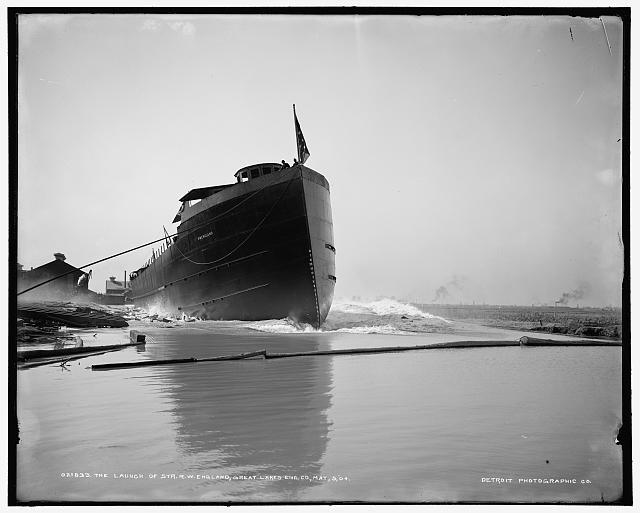 The prow of a steamship cuts through shallow water.