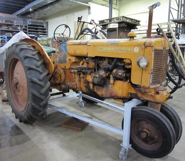 Tricycle-tired tractor with clam shell fenders parked inside a building.