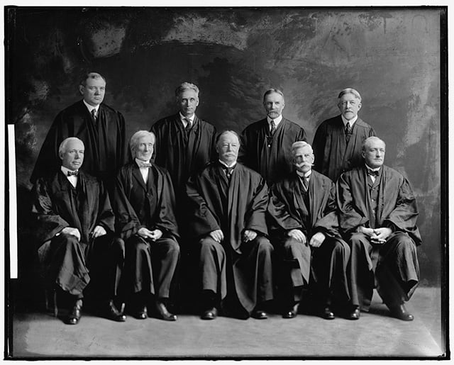 Nine men in black legal robes pose for a photograph.