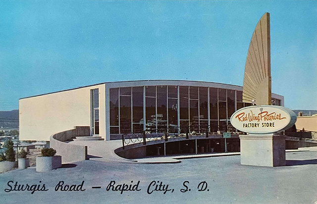 A building in a mid-twentieth-century modern style with floor-to-ceiling windows in front of a blue sky.