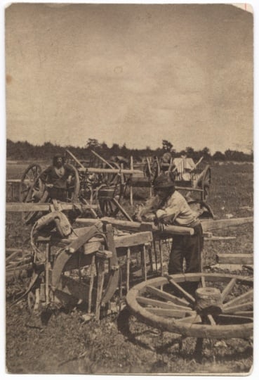 Black and white photograph of two men, probably Métis, preparing a Red River cart train at Pembina, 1856.