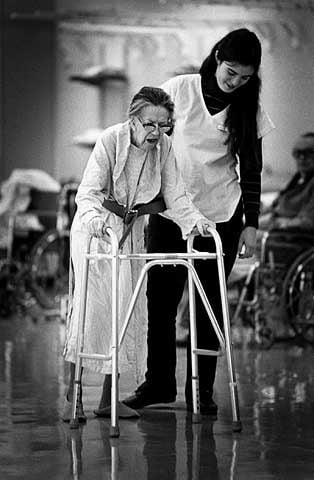 Therapist assists elderly stroke victim with a walker, Abbott-Northwestern Hospital, Sister Kenny Pavilion.