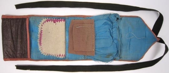 A soldier's housewife sewing kit made from a strip of leather with a twill-like finish and lined with silk.