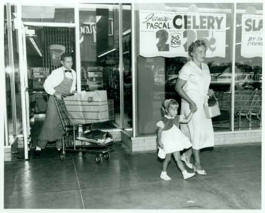 Employee Dick Liecting pushing a grocery cart for two shoppers at the Red Owl Store, Southdale Mall, Edina.