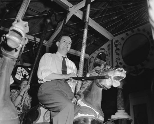 Black and white photograph of Hubert Humphrey riding the merry-go-round at the Minnesota State Fair, 1947.