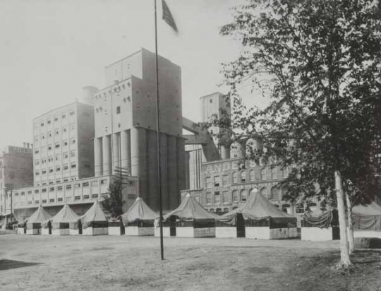 Black and white photograph showing the tents of D Company, First Minnesota Infantry, on guard duty at the Pillsbury mills, 1917.