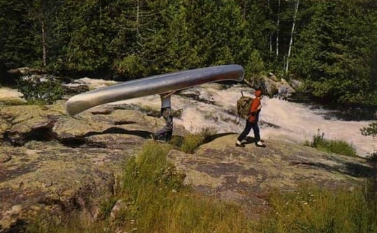 Color image of a group portaging a canoe in the Boundary Waters, ca. 1980.