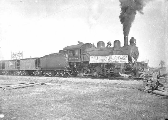 Black and white photograph of a train carrying first shipment of iron ore from the Kennedy Mine on the Cuyuna Iron Range, 1911.