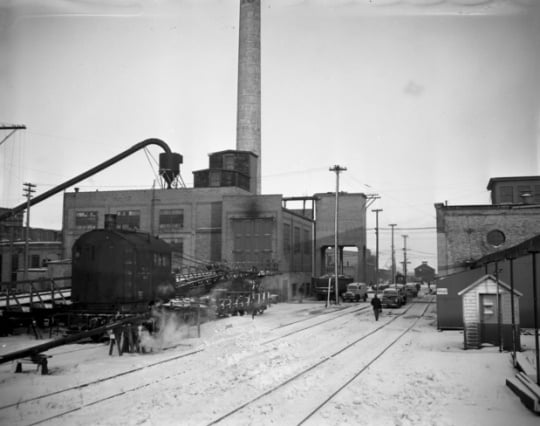 Black and white photograph of the Como Shops complex of the Northern Pacific Railway, located just south of Como Park in the St. Paul Midway, 1948. A railroad crane is parked next to the powerhouse building.