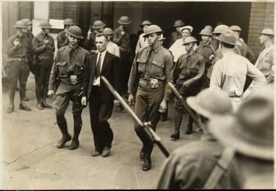 Black and white photograph of Vincent R. Dunne, strike committee member, arrested and held at the provost guard stockade at the State Fair grounds, 1934.