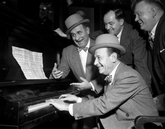 Black and white photograph of Jimmy Durante (back left) and Mayor Hubert H. Humphrey sing along with two unidentified men, 1946.