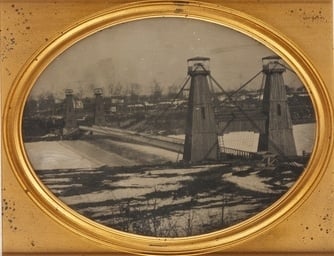 Black and white, daguerreotype-style photograph of the Hennepin Avenue Bridge, c.1857.