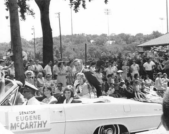 Black and white photograph of Eugene McCarthy in a parade, with daughters Ellen, Mary, and Margaret McCarthy, c.1964.