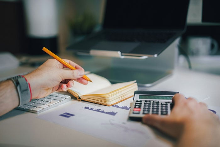 A person sitting at a desk with a calculator and a notebook.