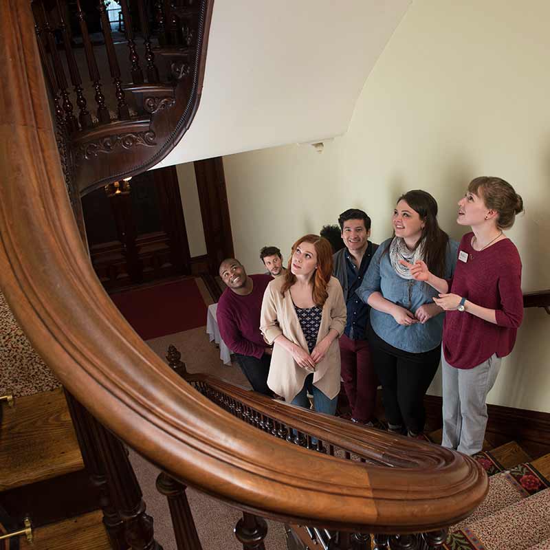 A group of people looking up an ornate staircase. A group of people looking up an ornate staircase.