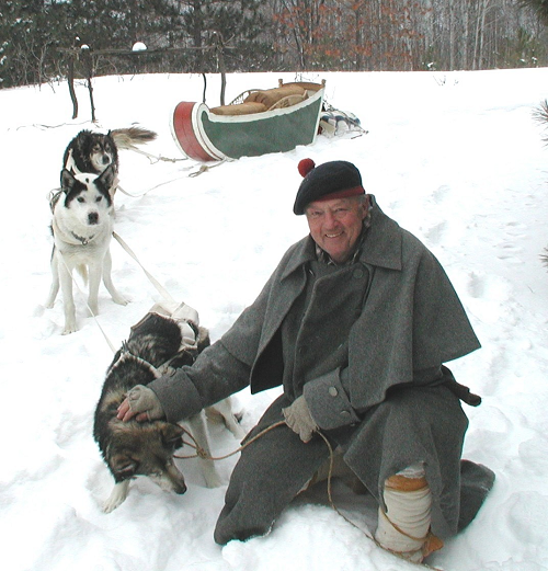 Volunteer in a costume with his dogs in a winter scene.