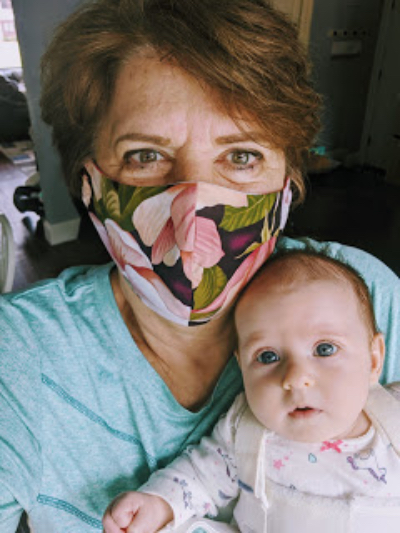 A grandma wears a mask while holding her granddaughter.