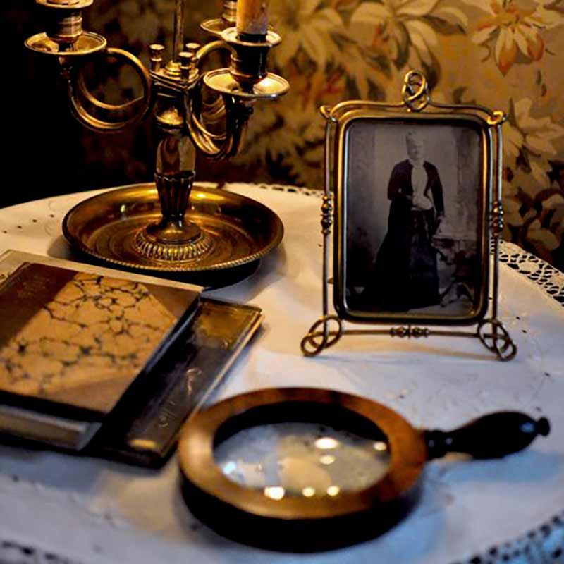 Antique magnifying glass resting on table next to antique photograph in frame