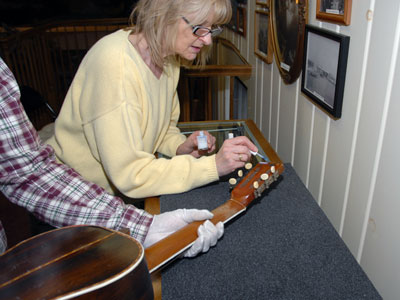 Woman adding an accession number on to guitar.